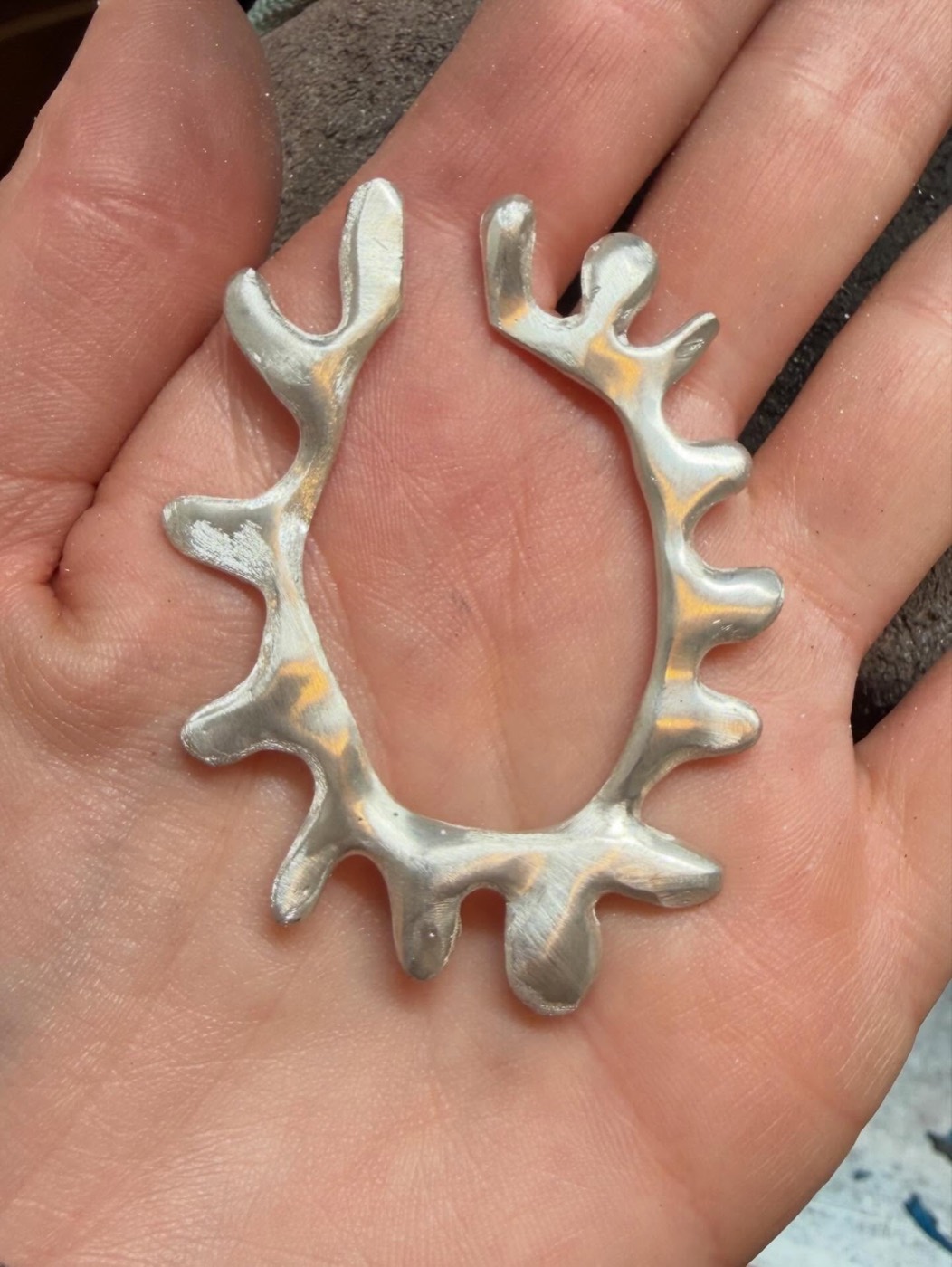A raw, unpolished silver hoop resting in the maker's palm