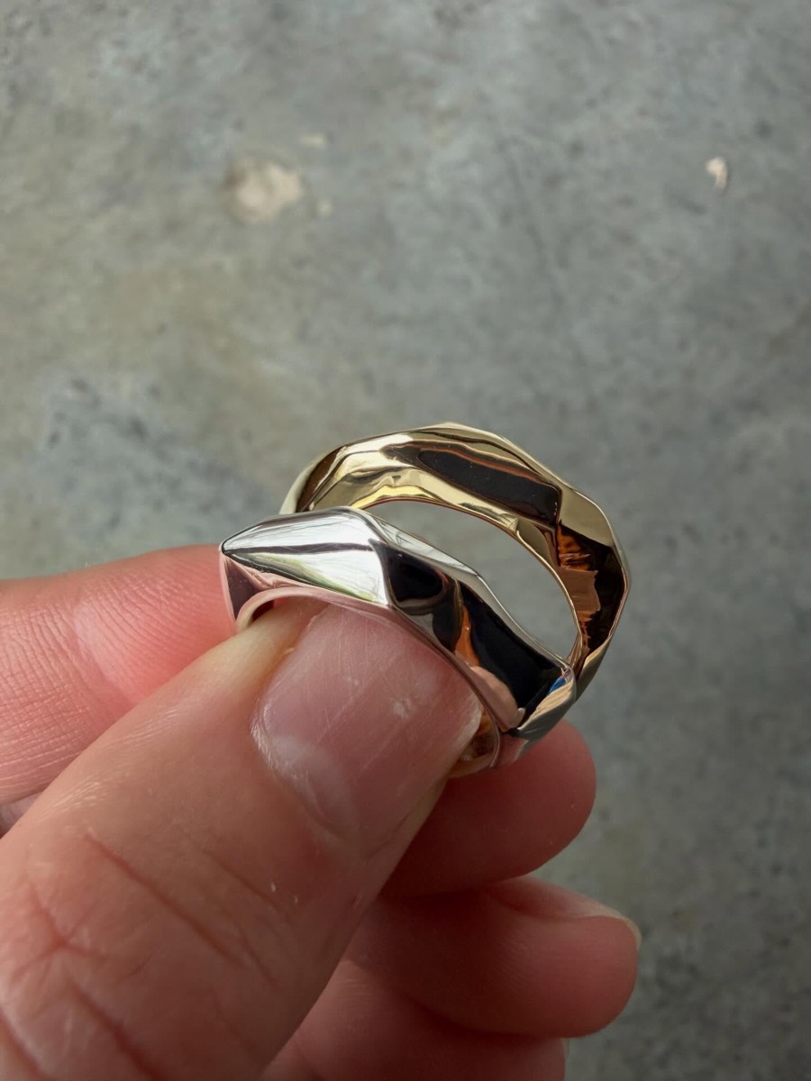 Facet Rings in solid gold and sterling silver held between fingertips
